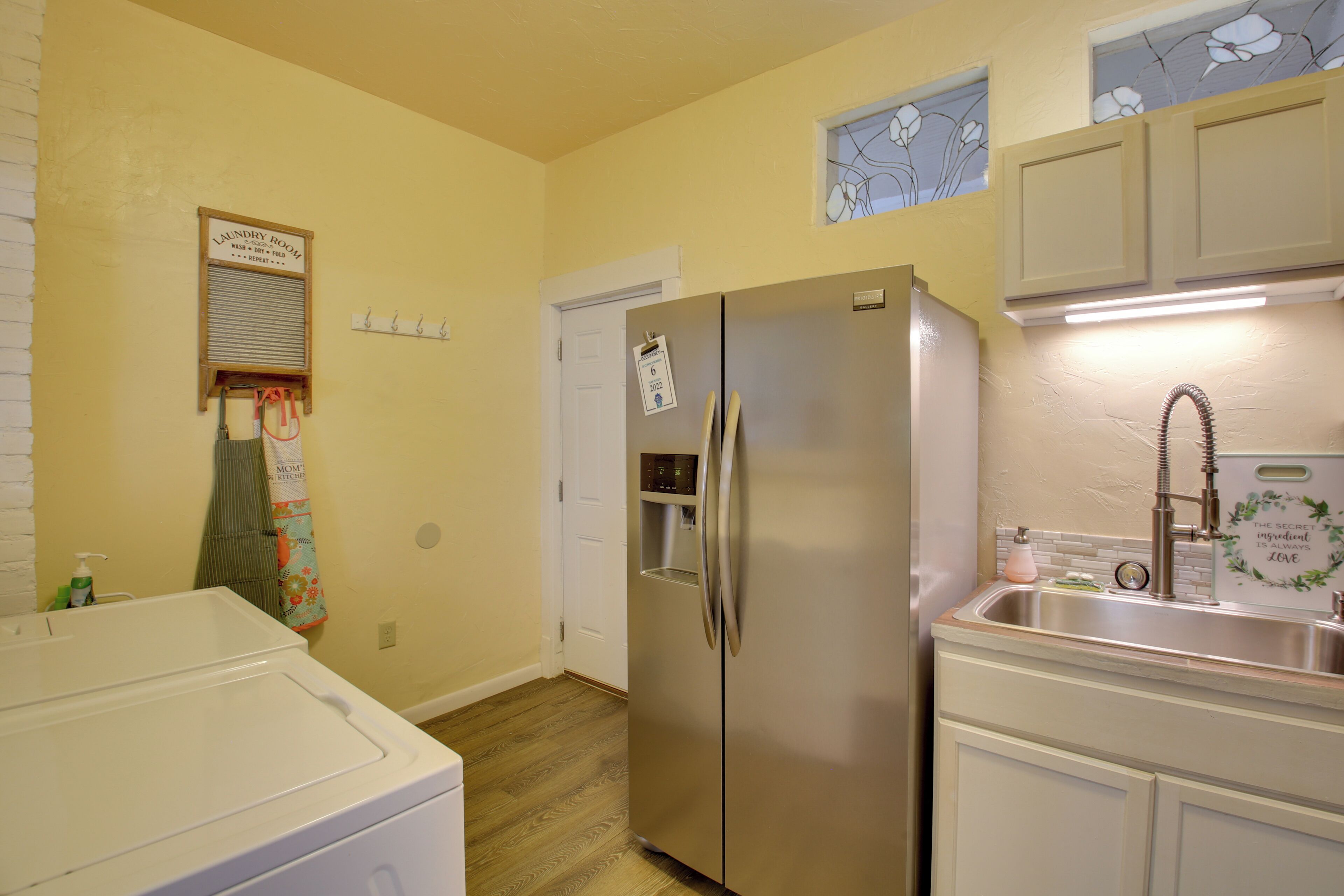 A laundry room with a washing machine, a refrigerator, and a sink.