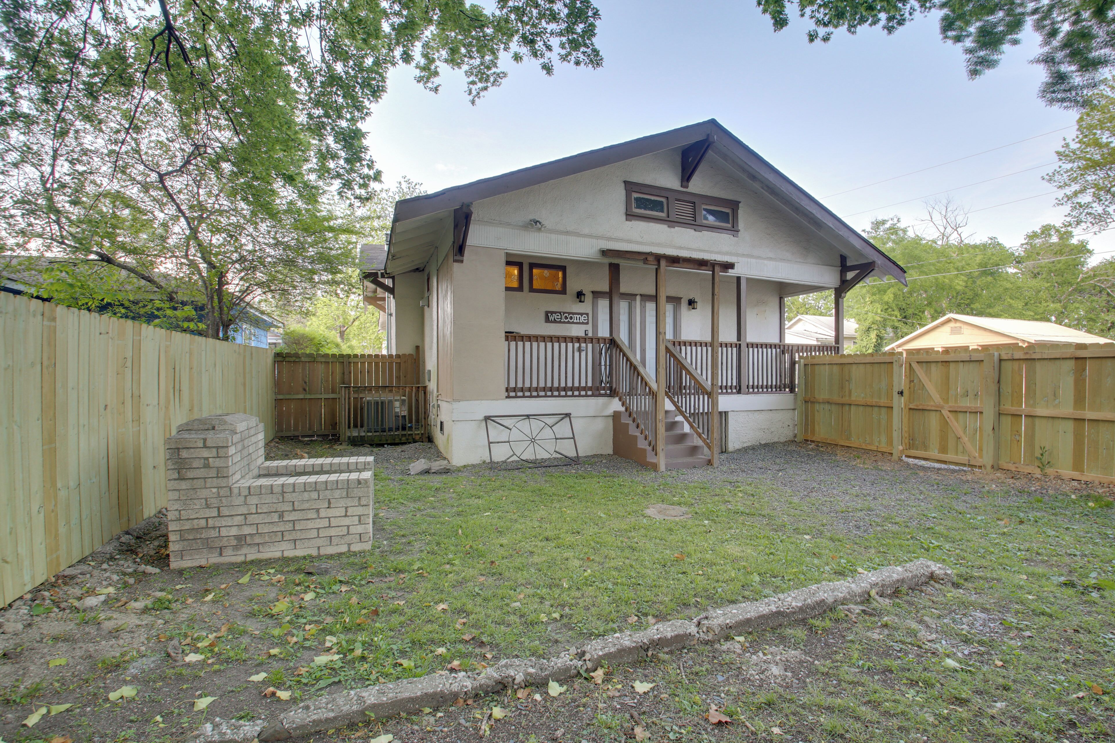 A two-story house with a 'welcome' sign, a wooden staircase, and a fenced backyard.