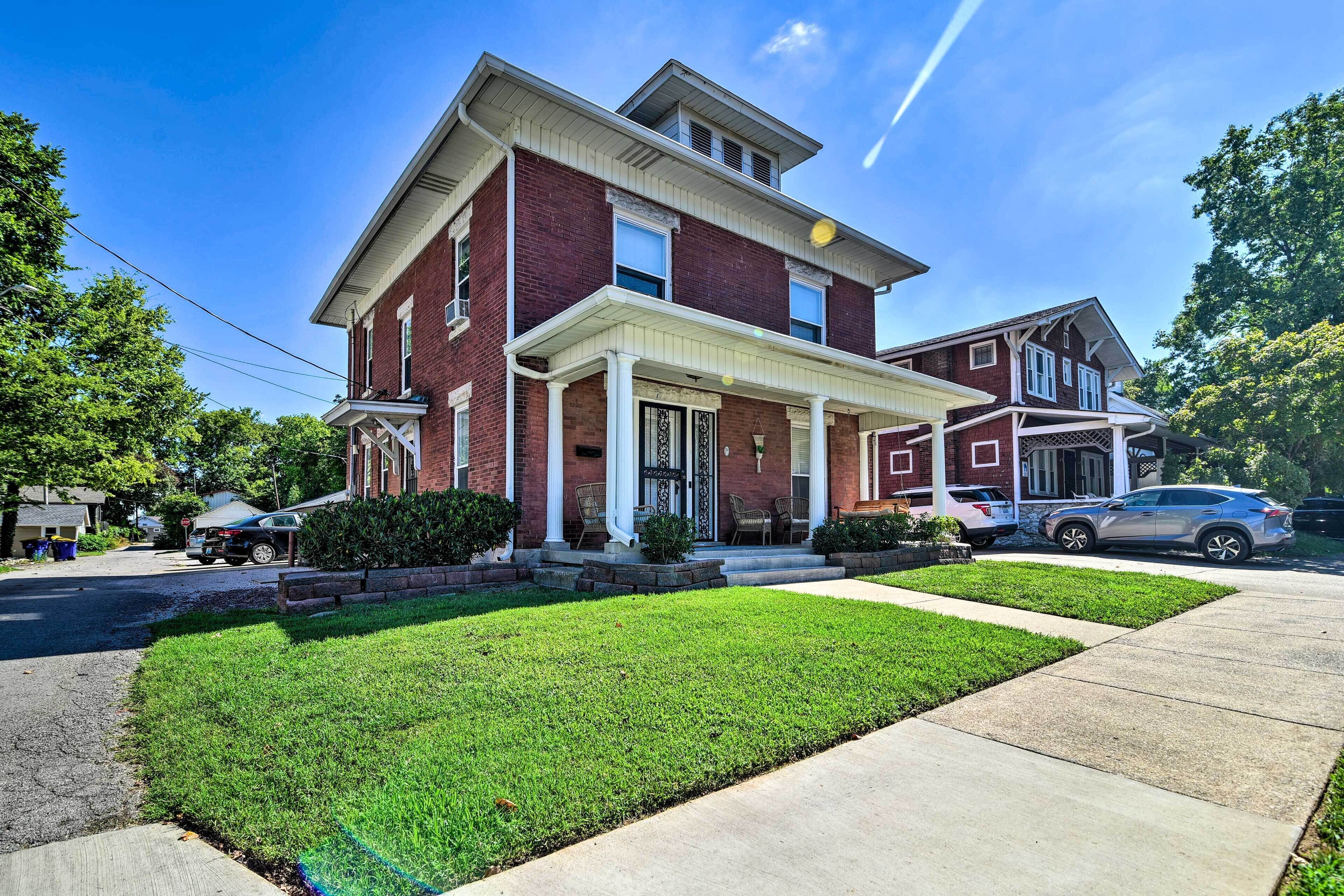 A two-story brick house with a front porch and a well-maintained lawn.