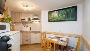 A compact kitchen with a microwave, kettle, and wooden table with chairs. - Cozy Alpine Apartment near Lake Bohinj,  Free Bikes & No Extra Fees (Bohinjska Bistrica)