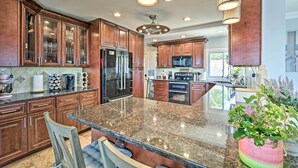 A spacious kitchen with granite countertops, wooden cabinets, and stainless steel appliances.