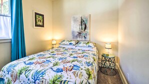 Une chambre à coucher avec un lit, deux lampes de chevet, une petite table et un tableau au mur.