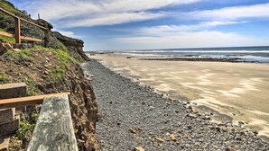Une plage rocheuse avec une promenade en bois qui mène à une falaise.