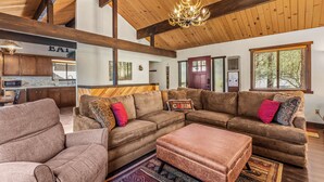 A spacious living area with a large sectional sofa, ottoman, and a chandelier. - 1 Mi to Slopes: Big Bear Ski Haven w/ Hot Tub (Big Bear Lake)