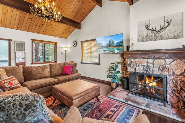 Ein gemütliches Wohnzimmer mit Kamin, einer großen Couch und einer Steinwand.