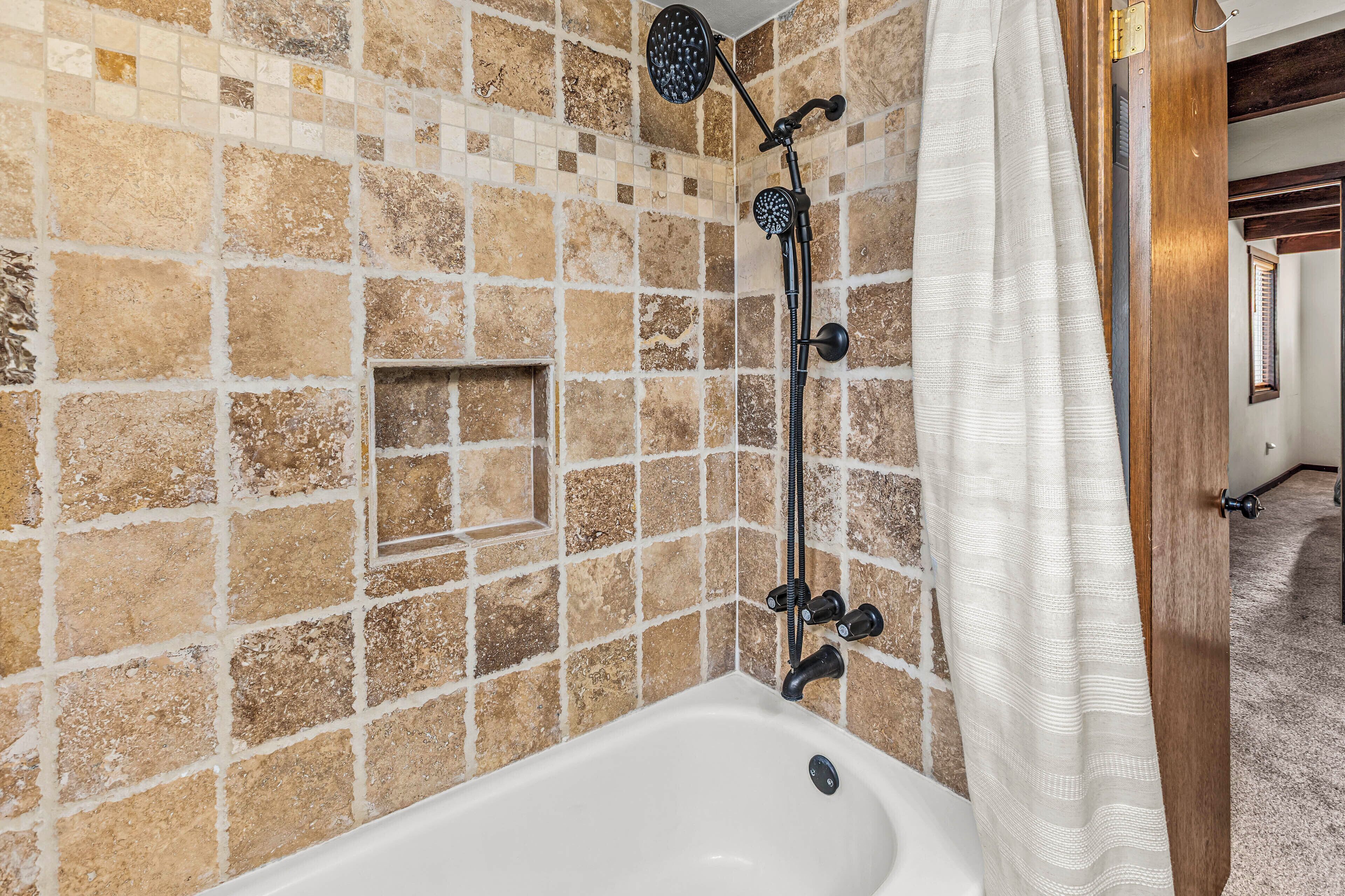 Une salle de bain avec une baignoire, une douche et des murs recouverts de mosaïques.