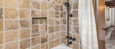 Une salle de bain avec une baignoire, une douche et des murs recouverts de mosaïques.