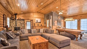 A cozy log cabin interior with a large sectional sofa, a wooden coffee table, and a pool table. - < 2 Mi to Lake: Big Bear City Cabin w/ Hot Tub! (Big Bear City)