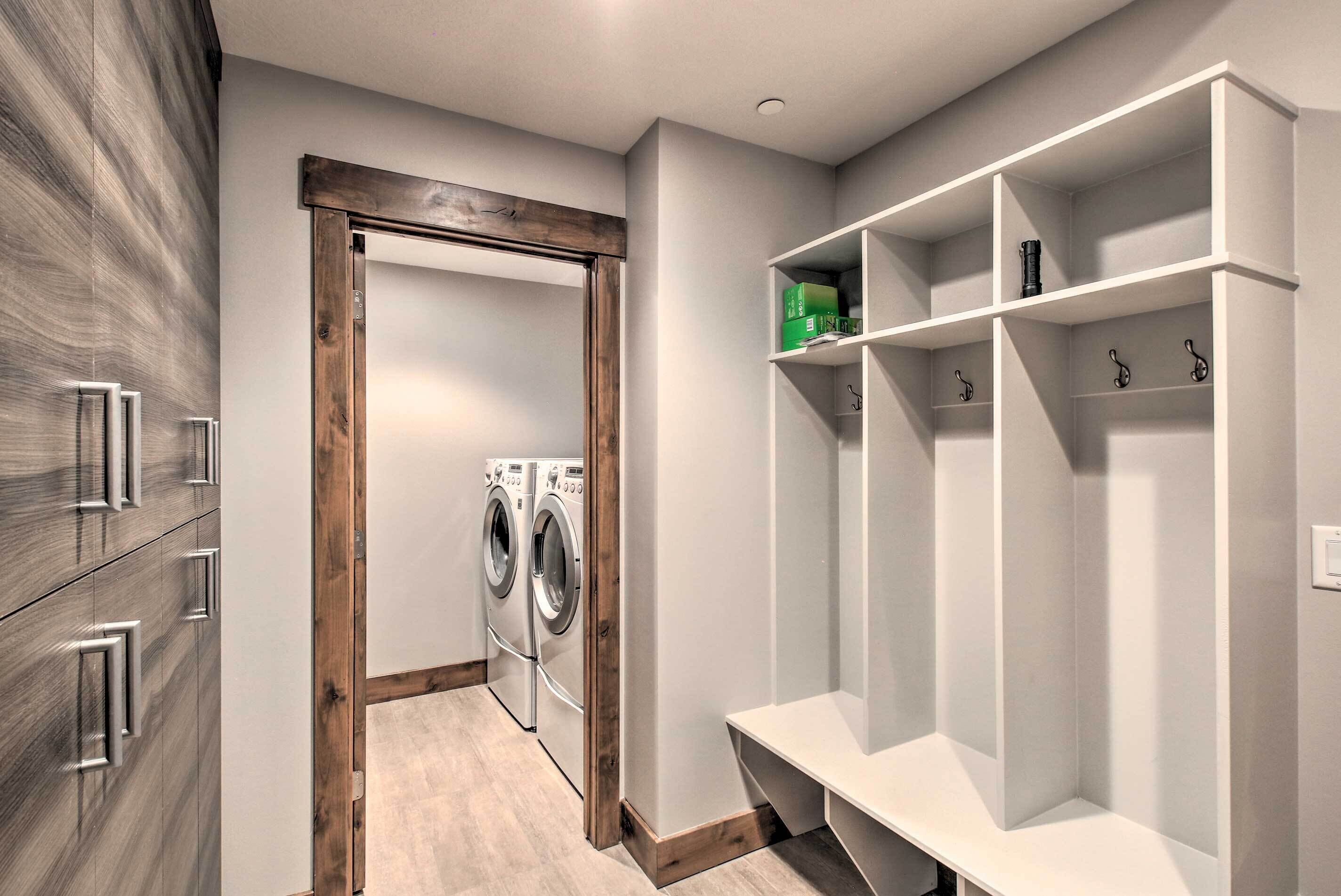 Une buanderie équipée d’un meuble en bois, d’un lave-linge et d’une étagère blanche agrémentée de crochets.