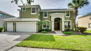 A two-story house with a garage, a front porch, and a palm tree.