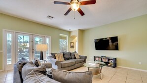 A living room with a sectional sofa, a coffee table, a TV, and a bookshelf.