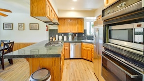 A kitchen with wooden cabinets, a stainless steel refrigerator, a built-in oven, and a granite countertop. - All-season Crestline Escape - 2 Mi to Lake! (Crestline)