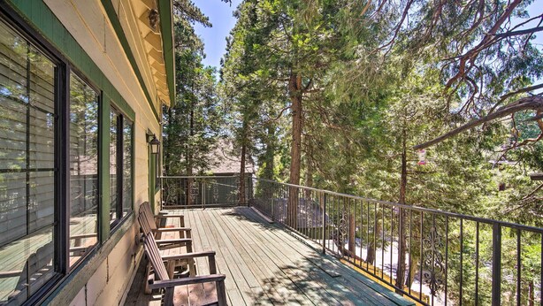 A wooden deck with benches, surrounded by trees and a building with large windows. - All-season Crestline Escape - 2 Mi to Lake! (Crestline)