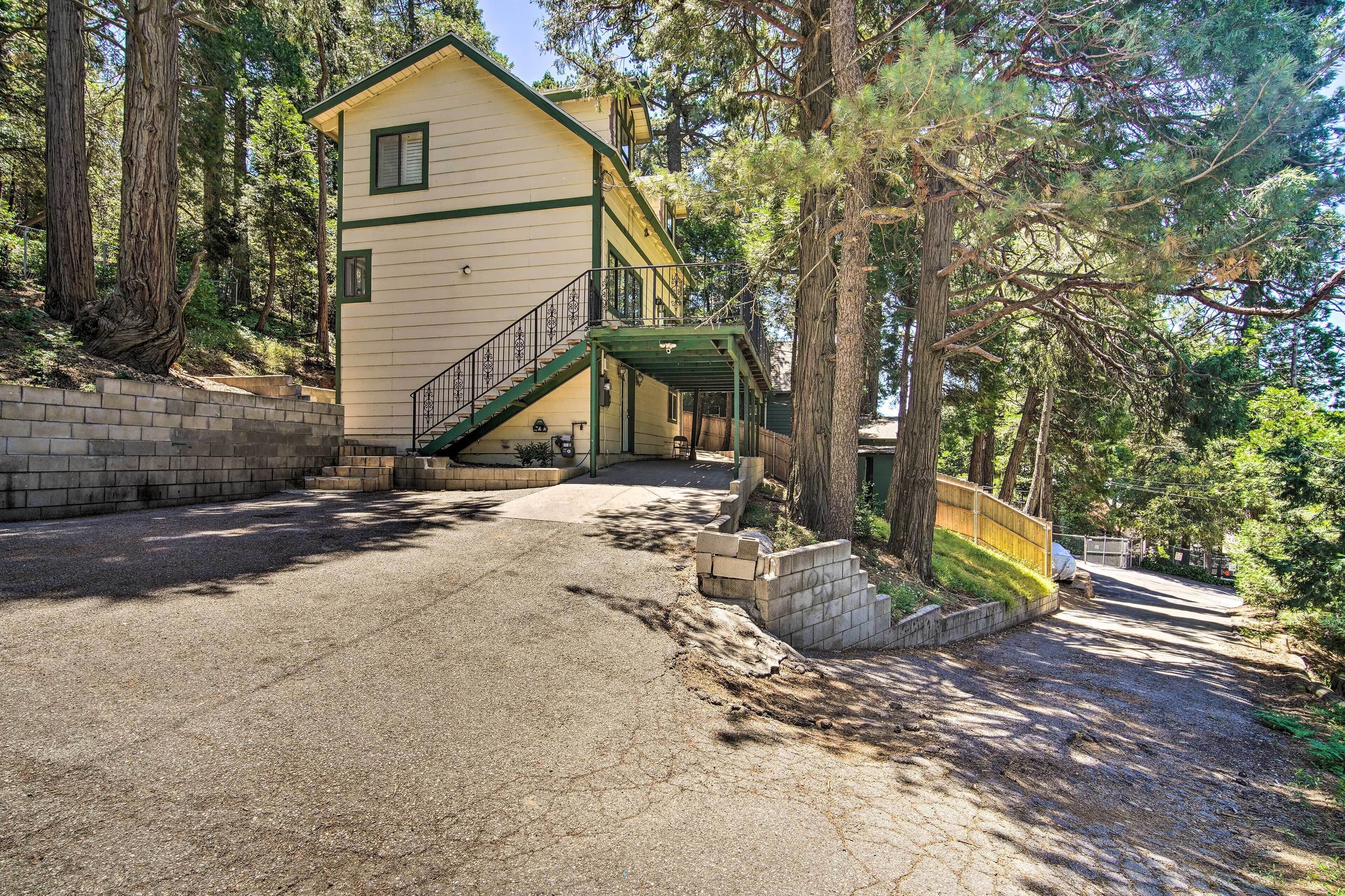 A two-story house with a green staircase leading to a balcony, surrounded by trees.