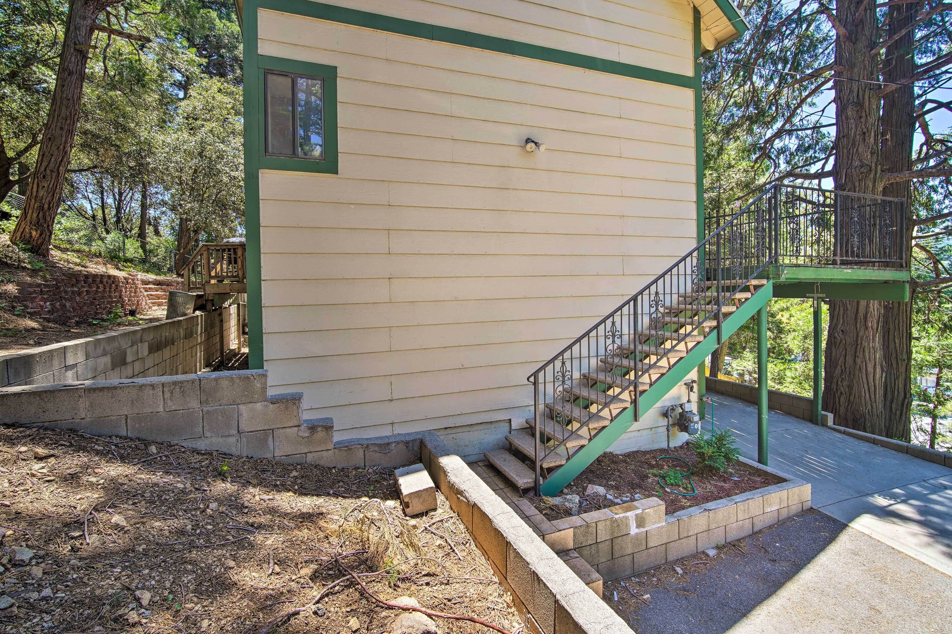 Une maison à l’extérieur vert, avec une terrasse en bois et un escalier menant à un balcon.