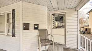 A white wooden porch with a metal chair, a door, and a window with blinds. - Springfield Vacation Rental: 1 Mi to Downtown (Springfield)