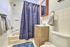 Une salle de bain avec une baignoire, un meuble en bois, des toilettes et un rideau de douche bleu.
