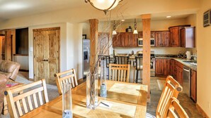 A spacious dining area with a wooden table and chairs, a chandelier, and wooden cabinets in the background. - Chic Pagosa Springs Condo w/ Porch - Walk to Shops (Pagosa Springs)