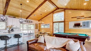 A spacious living area with a leather sofa, wooden ceiling beams, and a pool table. - Custom-built Gem w/ Kayaks & Games in Big Bear! (Big Bear City)
