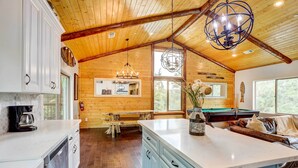 A spacious kitchen with wooden walls, a large island, and a dining area with a bench. - Custom-built Gem w/ Kayaks & Games in Big Bear! (Big Bear City)