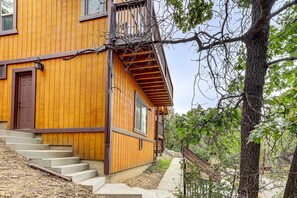 A wooden house with a brown door, large windows, and a staircase leading to the entrance. - Custom-built Gem w/ Kayaks & Games in Big Bear! (Big Bear City)