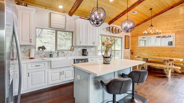A modern kitchen with white cabinets, a large island, and bar stools. - Custom-built Gem w/ Kayaks & Games in Big Bear! (Big Bear City)