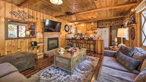 A cozy cabin interior with a wooden ceiling, a fireplace, a television, and a kitchen area. - < 3 Mi to Lake: Pet-friendly Big Bear Cabin (Big Bear Lake)