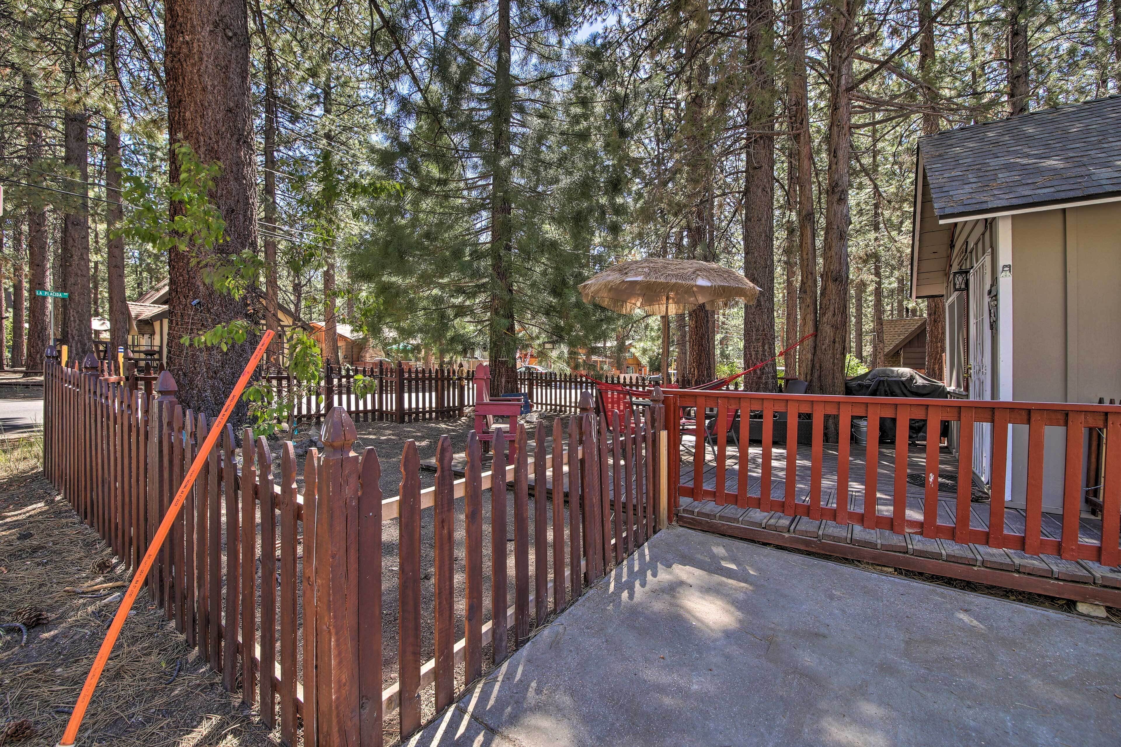 A wooden fence, a concrete pathway, and a building with a sloped roof.