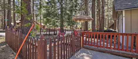 A wooden fence, a concrete pathway, and a building with a sloped roof.