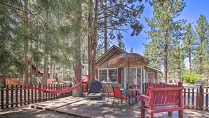 A wooden deck with a red bench, a thatched-roof structure, and a dining area with chairs and a table. - < 3 Mi to Lake: Pet-friendly Big Bear Cabin (Big Bear Lake)