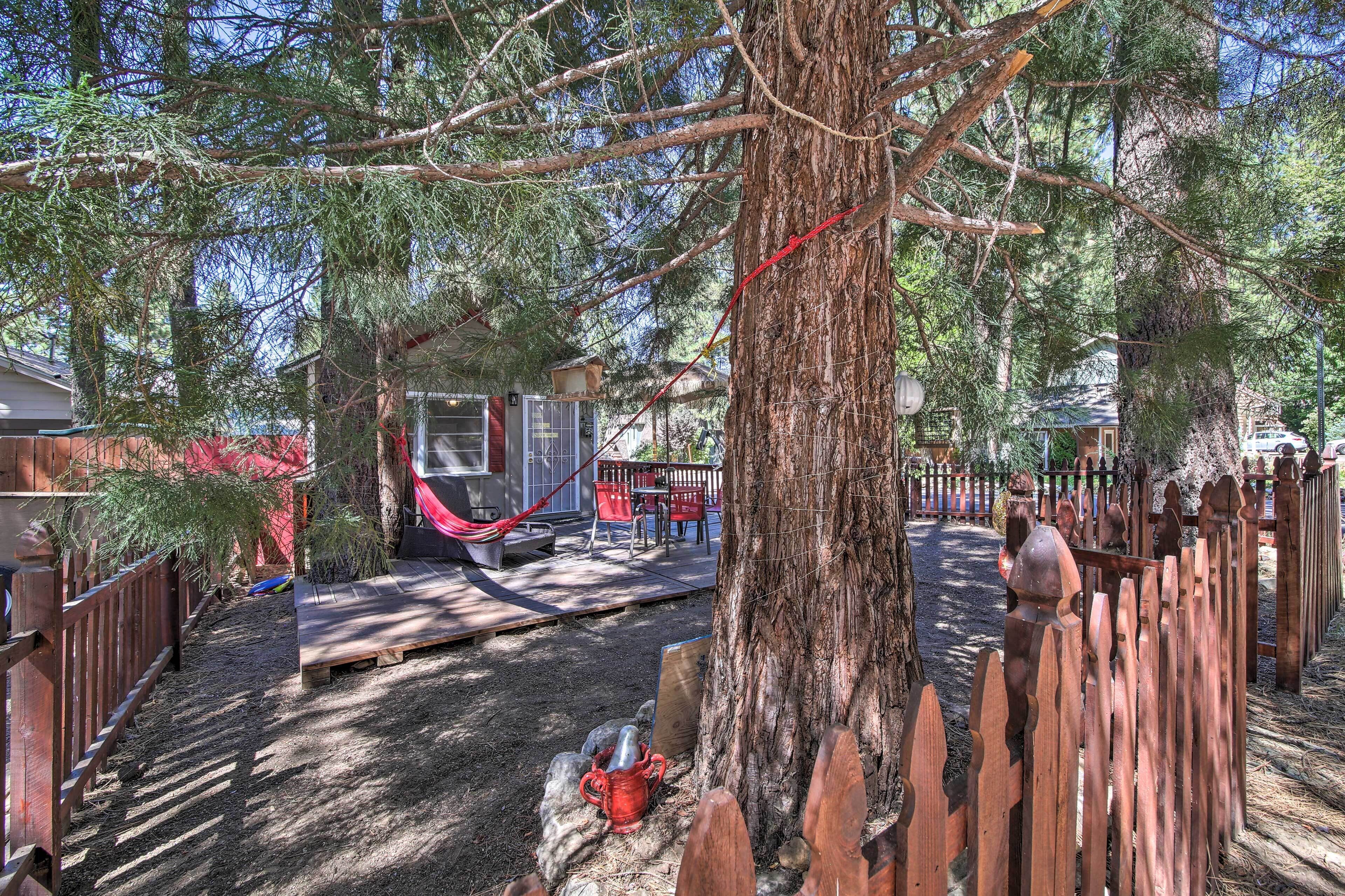 A fenced backyard with a hammock, a wooden deck, and a small shed.