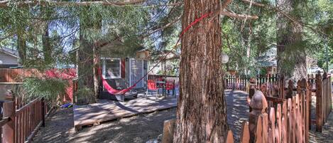 A fenced backyard with a hammock, a wooden deck, and a small shed.