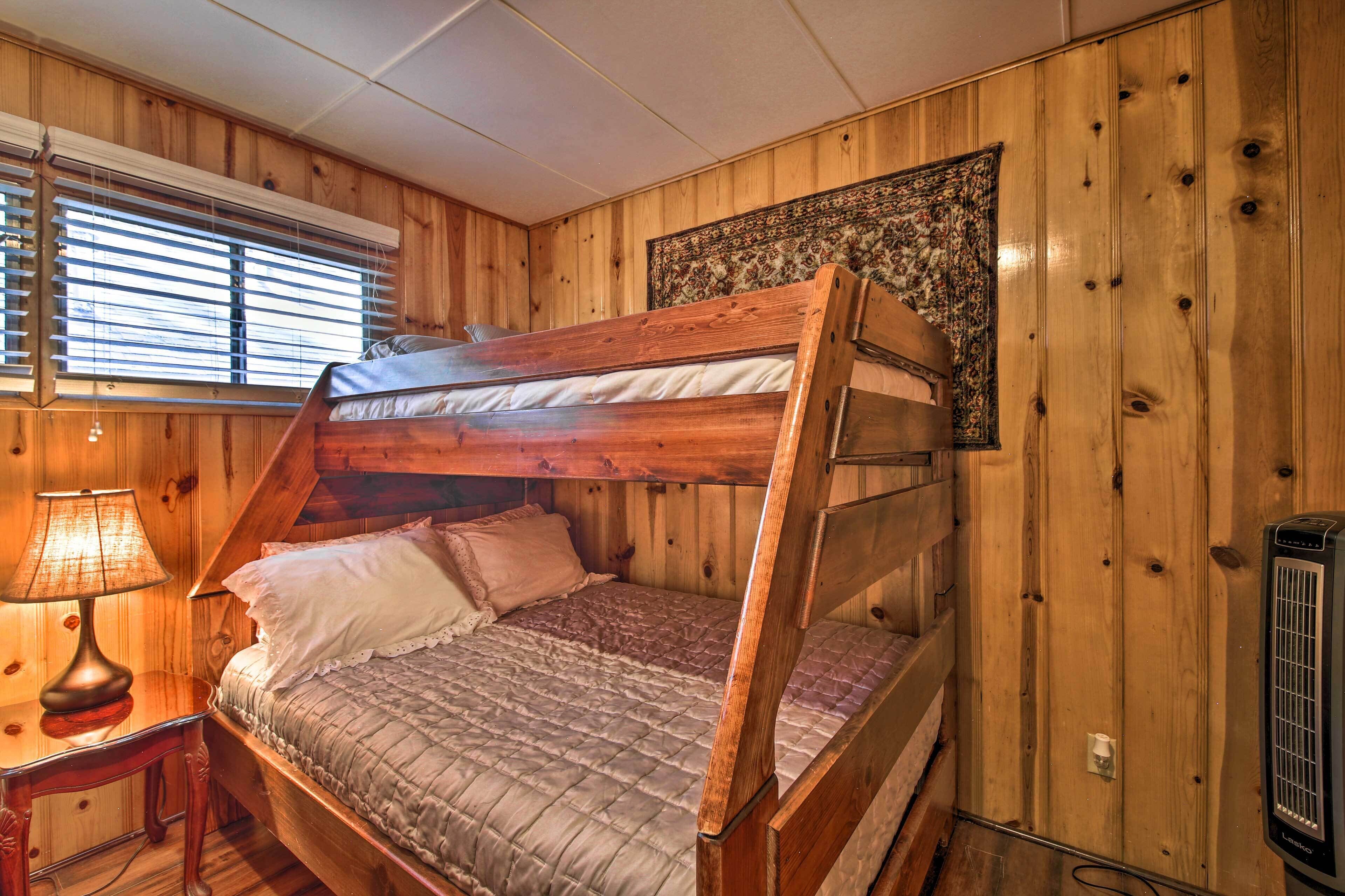A bunk bed in a wooden room with a window, a lamp, and a heater.