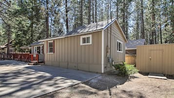 A single-story cabin with a sloped roof, a front porch, and a fenced yard.