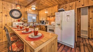 A wooden cabin kitchen with a central island, white appliances, and a clock on the wall. - < 3 Mi to Lake: Pet-friendly Big Bear Cabin (Big Bear Lake)