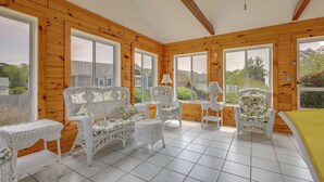 A room with wooden walls and large windows, furnished with wicker chairs and tables. - 1 Mi to Beach: Quiet West Dennis Escape w/ Sunroom (West Dennis)
