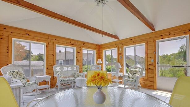 A room with a glass table, wicker chairs, and a vase with yellow flowers. - 1 Mi to Beach: Quiet West Dennis Escape w/ Sunroom (West Dennis)