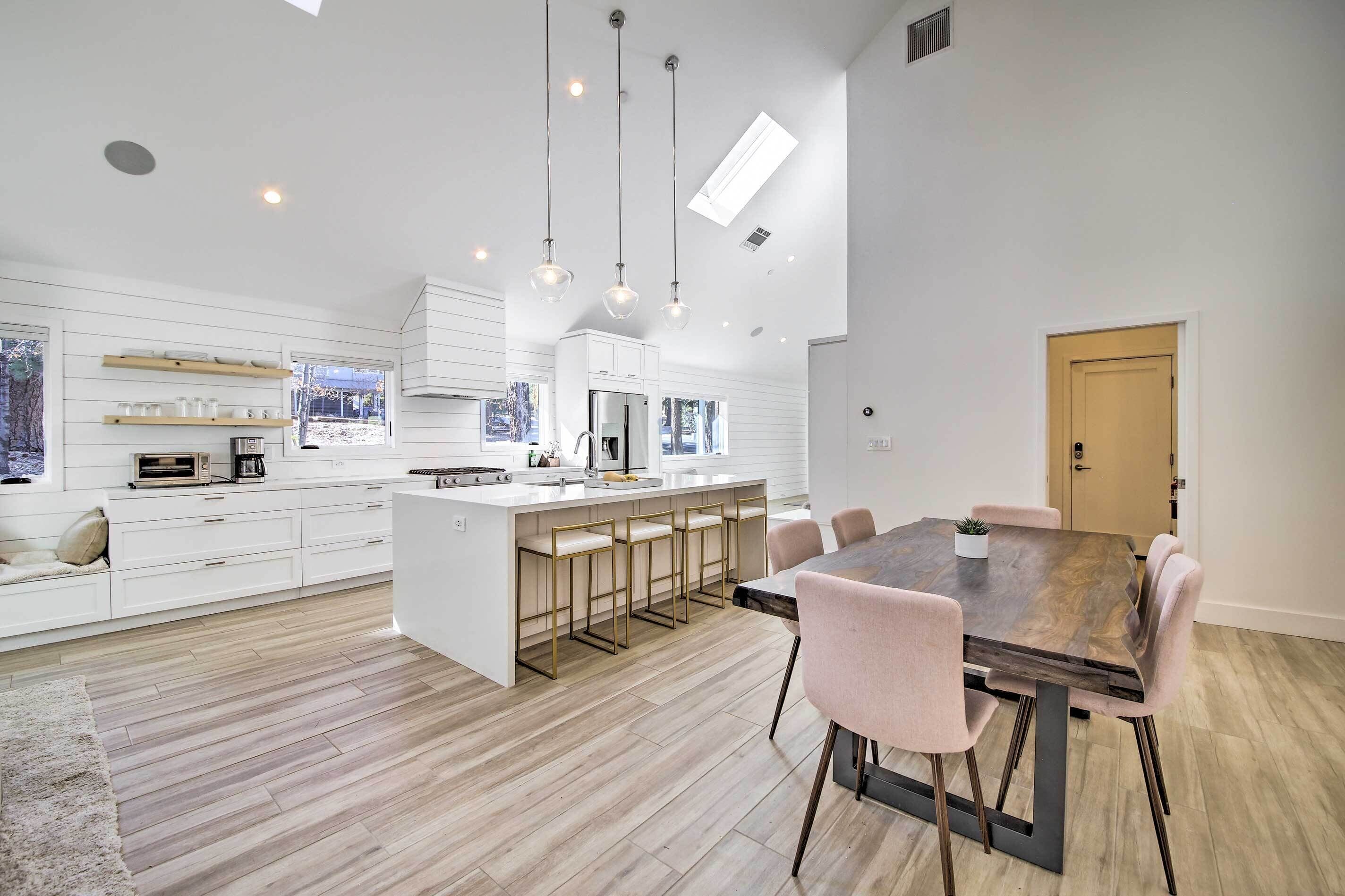 A modern kitchen with white cabinetry, a central island with bar stools, and pendant lighting.