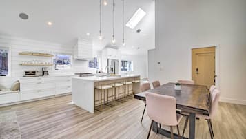 A modern kitchen with white cabinetry, a central island with bar stools, and pendant lighting.