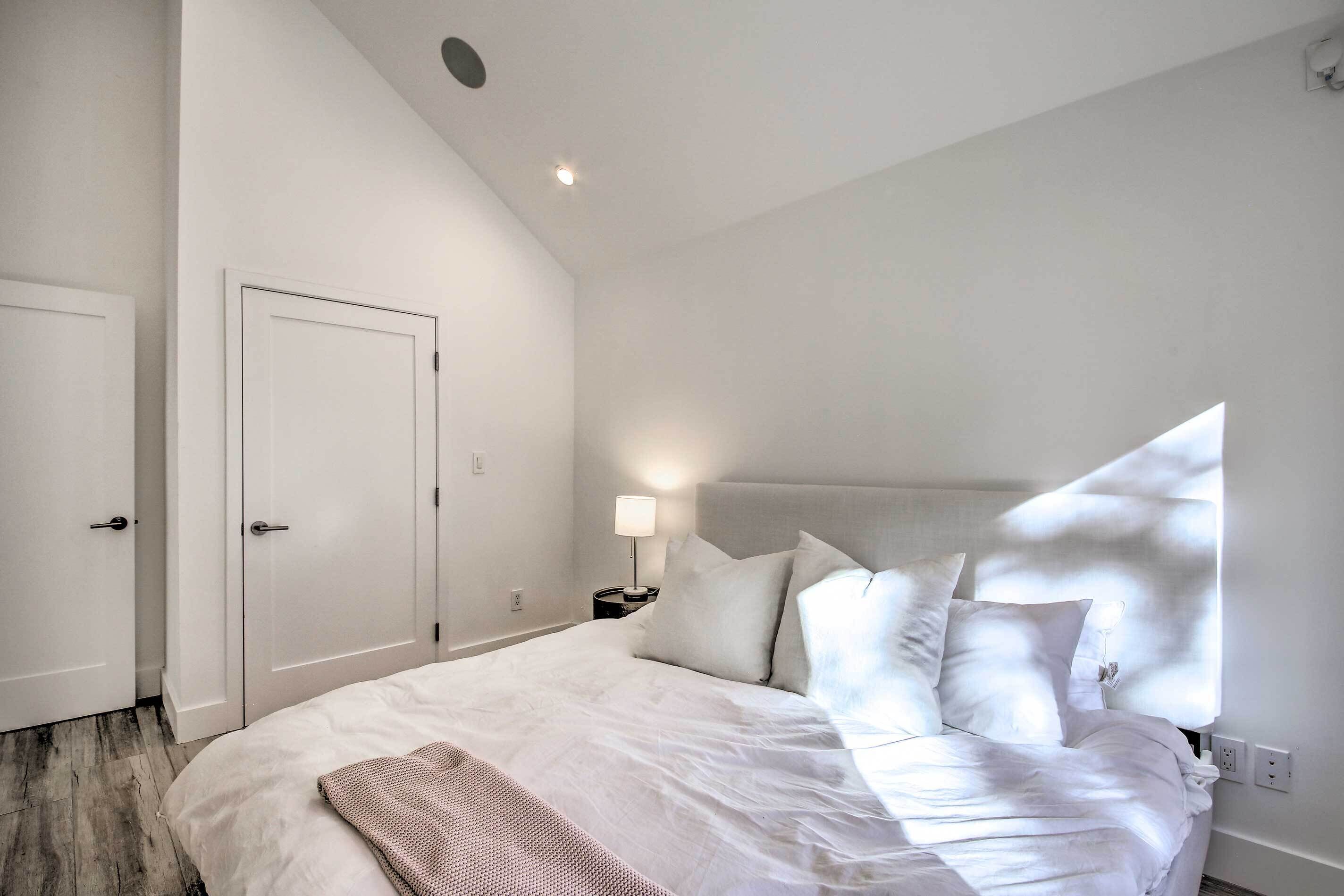 A bedroom with a large bed, a nightstand with a lamp, and a door.