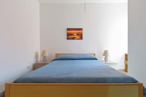 A bedroom with a bed, two bedside tables with lamps, a painting on the wall, and a nightstand with a lamp. - 3337 Residence Garden Sea - PP by Barbarhouse (Porto Cesareo)