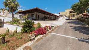 A building with a covered patio, surrounded by potted plants and flowers. - 3337 Residence Garden Sea - PP by Barbarhouse (Porto Cesareo)