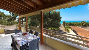 A covered outdoor dining area with a table set for four, overlooking a coastal landscape. - 3337 Residence Garden Sea - PP by Barbarhouse (Porto Cesareo)