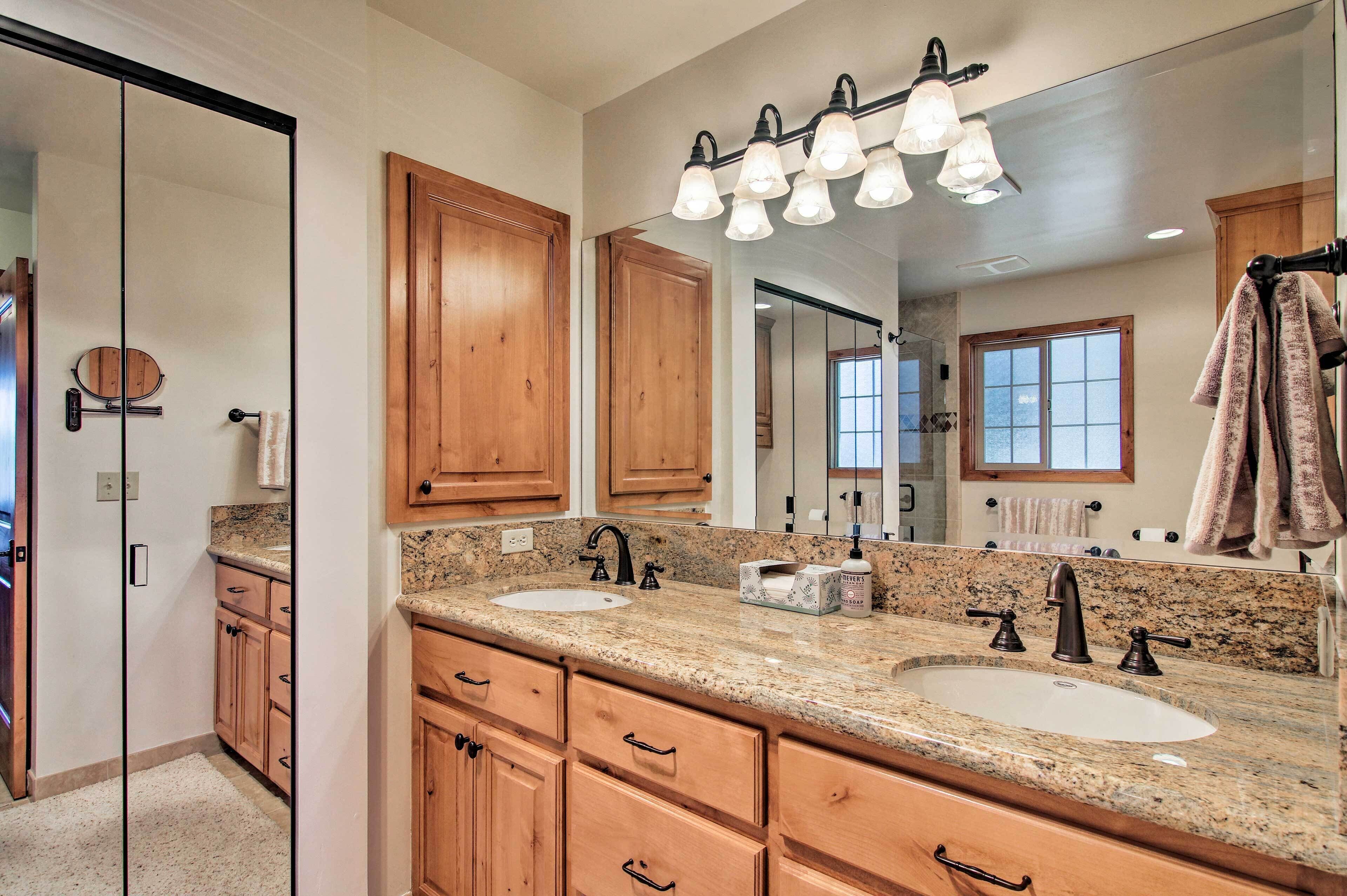A bathroom with two sinks, wooden cabinets, a large mirror, and a ceiling light fixture.