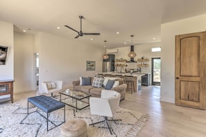 A spacious living room with a sofa, armchairs, and a coffee table. A kitchen is visible in the background with a dining area. - Stunning Wine Country Gem With Hot Tub + Patio! (Sonoma)