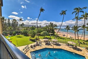A pool area with a view of the beach and palm trees. - Luxury Oceanfront Mana Kai Resort Condo (Kihei)