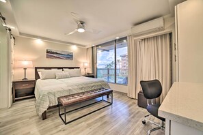 A modern hotel room with a large bed, a desk, and a view of the cityscape. - Luxury Oceanfront Mana Kai Resort Condo (Kihei)
