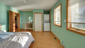 Un dormitorio con cama, cómoda, puerta, ventana y ventilador de techo.