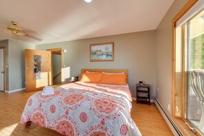A bedroom with a bed, a painting, a window, and a door.