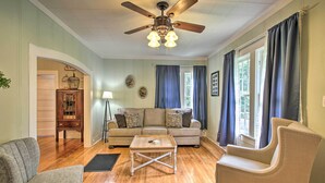 A living room with a wooden floor, a ceiling fan, a sofa, a coffee table, and a chair. - 1/2 Mi to Hot Springs Nat'l Park: Cottage w/ Patio (Hot Springs)